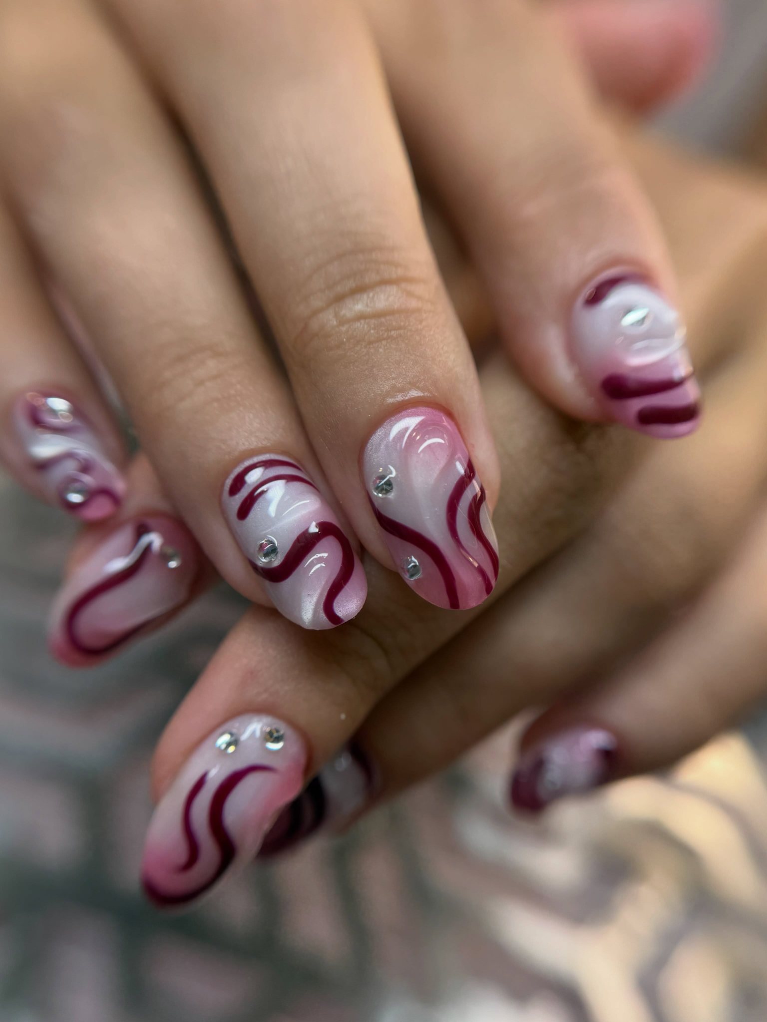 Nail art met bordeaux swirls en strass-steentjes